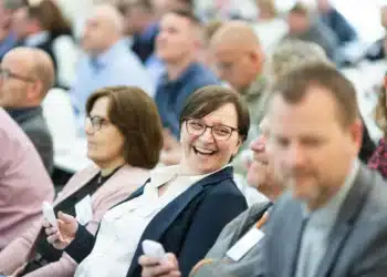 Fastholdelse af medarbejdere - hvad skal der til - fokus på smilende kvinde i stor forsamling