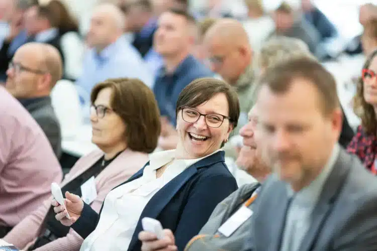 Fastholdelse af medarbejdere - hvad skal der til - fokus på smilende kvinde i stor forsamling