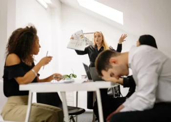 Konflikter på arbejdspladsen mellem 3 personer og chef. Manden hviler panden på bordpladen