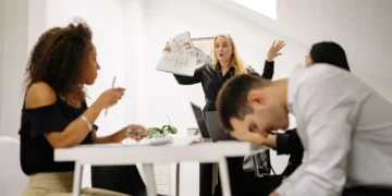 Konflikter på arbejdspladsen mellem 3 personer og chef. Manden hviler panden på bordpladen