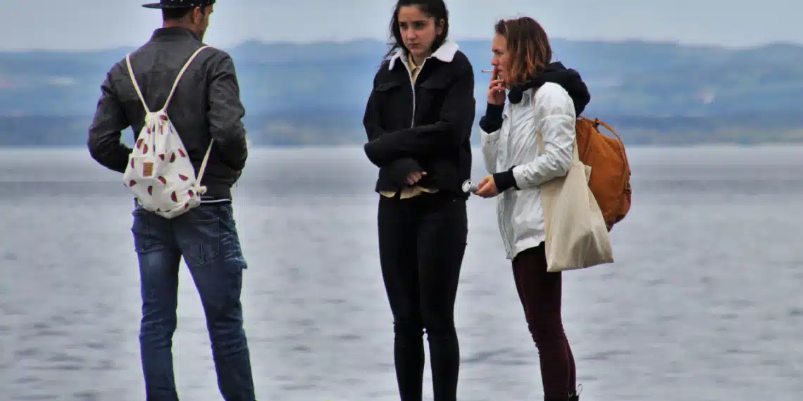 Den gode samtale - 2 kvinder og 1 mand snakker på strand. Den ene kvinder ryger en cigaret