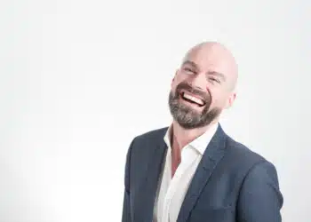 Faglig ledelse - den professionelle mand i jakkesæt og smilende på hvid baggrund