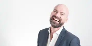 Faglig ledelse - den professionelle mand i jakkesæt og smilende på hvid baggrund