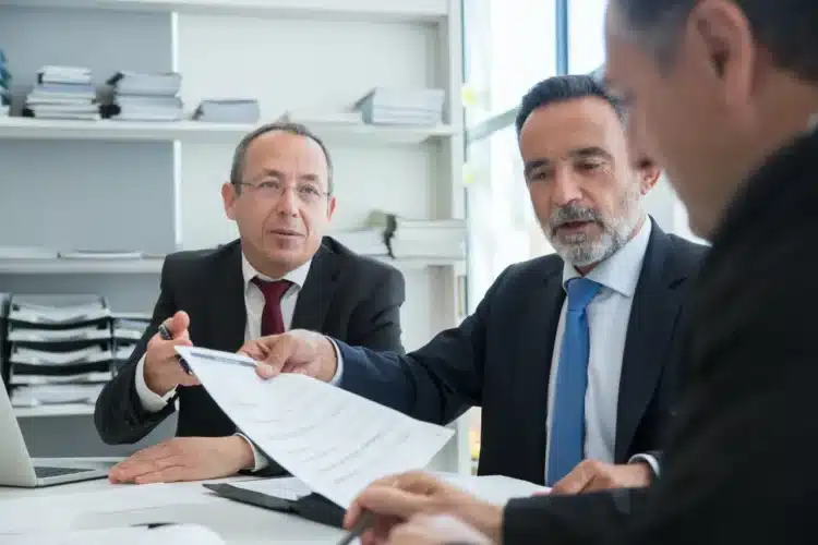 Ledelsesstil 6 ledelsesstile du som leder skal kende - 3 mænd i samtale om et stykke papir