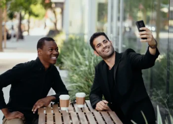 To mænd sidder på cafe og drikker kaffe og tager en selfie som udtryk for den gode samtale