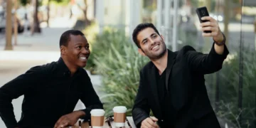 To mænd sidder på cafe og drikker kaffe og tager en selfie som udtryk for den gode samtale
