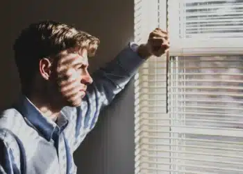 kendetegn dårlig leder mand kigger ud af vinduet med persienner