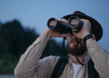 Mand holder kikkert for øjnene som udtryk for strategisk ledelse i modsætning til mikroskopet.