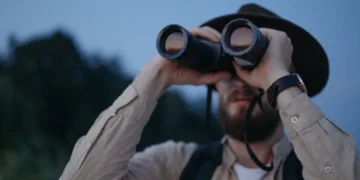 Mand holder kikkert for øjnene som udtryk for strategisk ledelse i modsætning til mikroskopet.