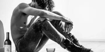 dårligt arbejdsmiljø - mand sidder på gulv dybt bedrøvet med en flaske vin ved siden af ham