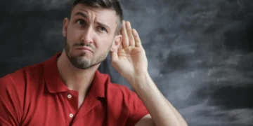 Demokratisk leder - mand i rød trøje sidder med hånd bag øret og lytter