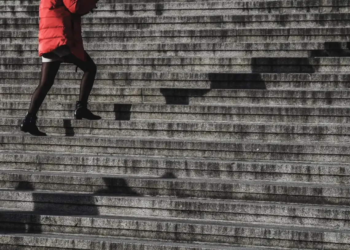 Konflikttrappen kvinde i rød jakke går op af trapper