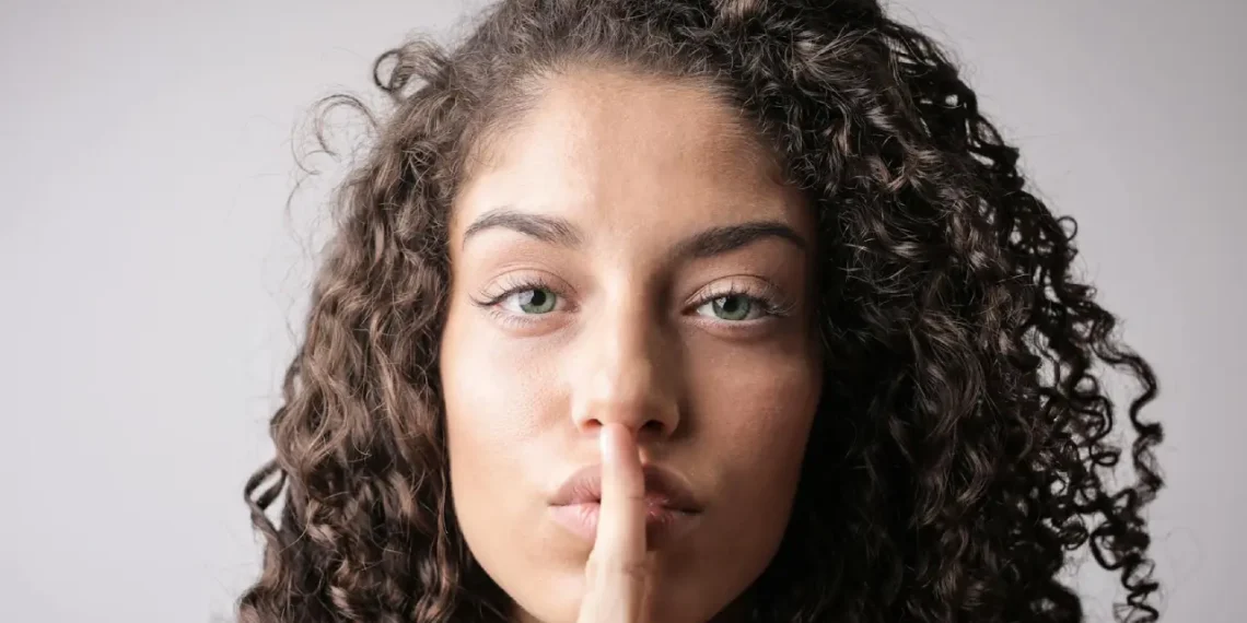 Kvinde holder pegefinger på læber i quiet quitting.