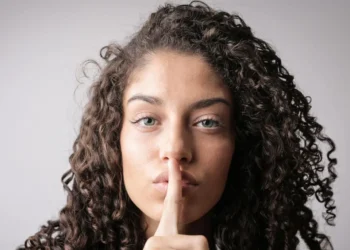 Kvinde holder pegefinger på læber i quiet quitting.