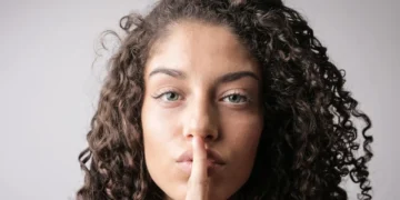 Kvinde holder pegefinger på læber i quiet quitting.