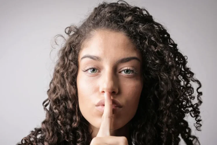 Kvinde holder pegefinger på læber i quiet quitting.