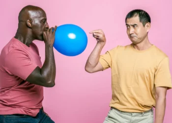 Mand blæser ballon op mens anden mand peger på den som udtryk for tryghedscirklen