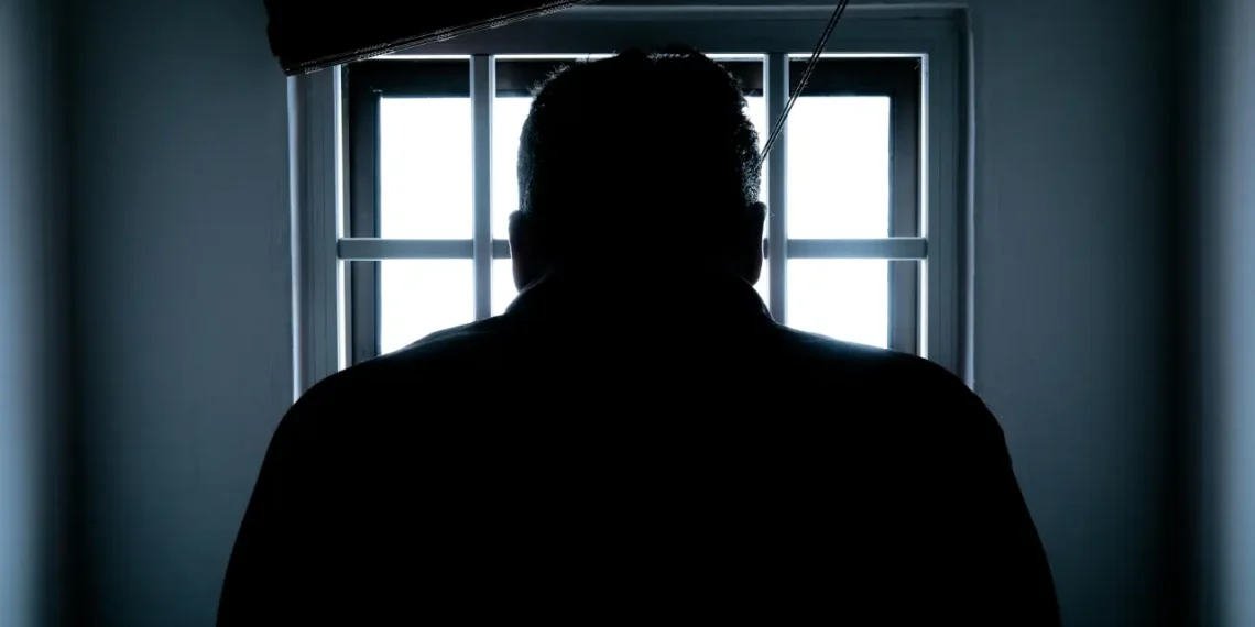 fængsel i danmark - mand står foran tremmer med ryggen til