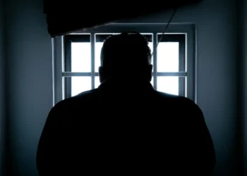 fængsel i danmark - mand står foran tremmer med ryggen til