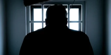 fængsel i danmark - mand står foran tremmer med ryggen til