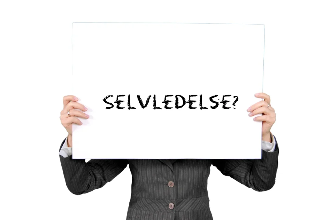 Selvledelse skrevet med sort kridt på whiteboard holdt af et menneske