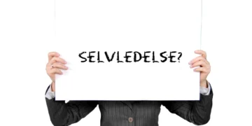 Selvledelse skrevet med sort kridt på whiteboard holdt af et menneske