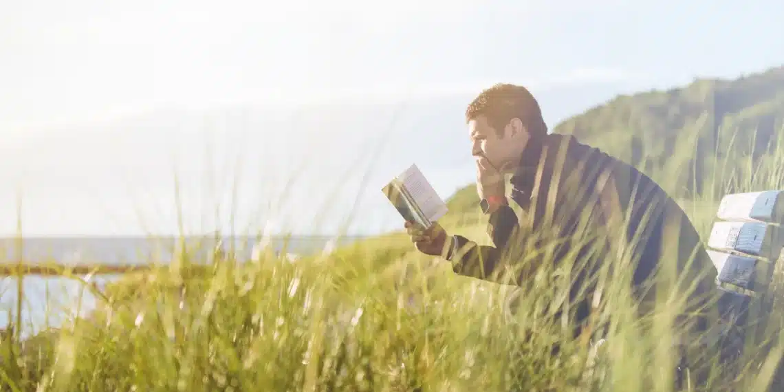 dunning-kruger-effekten mand sidder og læser i en bog på bænk i klitterne