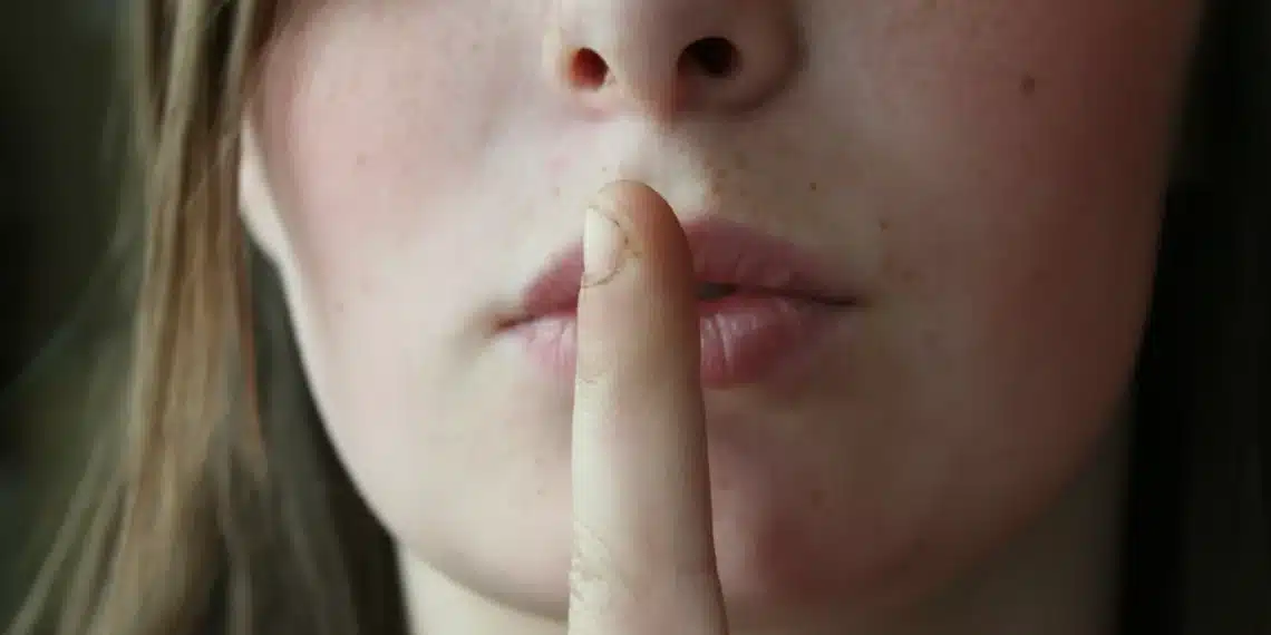 tavshed i ledelse - kvinde holder pegefingeren op for munden