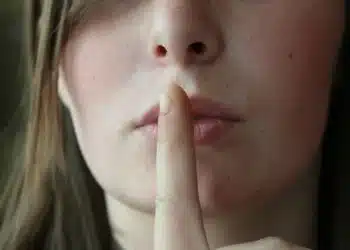 tavshed i ledelse - kvinde holder pegefingeren op for munden