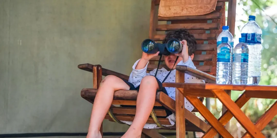 Dreng sidder med kikkert i havestol som udtryk for sensemaking