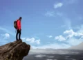 Motivationsfaktorer - mand står på toppen af bjerg helt oppe i skyerne