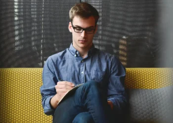 Mand sidder dybt koncentreret og skriver ledelsesprincipper ned på papir