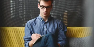 Mand sidder dybt koncentreret og skriver ledelsesprincipper ned på papir