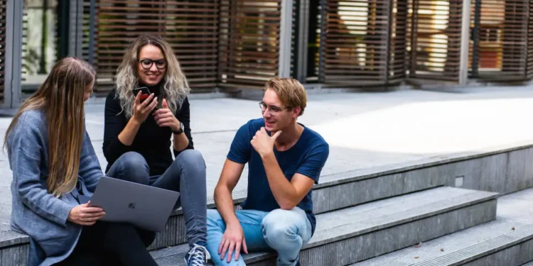 Kommunikation - her 3 studerende sidder på trappe med MacBook udenfor universitet som billede på kommunikation