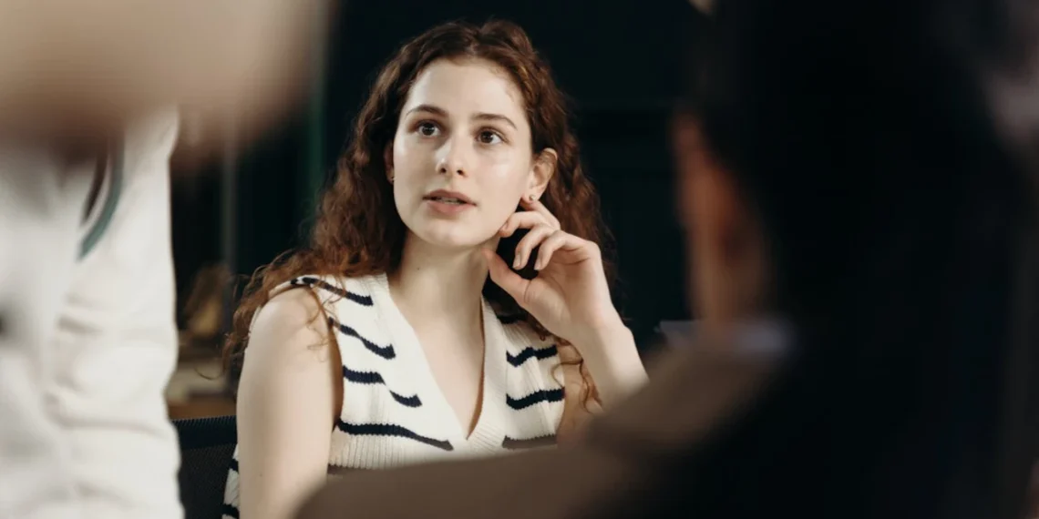 Kvinde taler assertivt og fotograferes tæt på mellem 2 andre mennesker