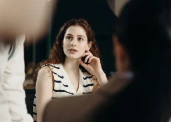 Kvinde taler assertivt og fotograferes tæt på mellem 2 andre mennesker