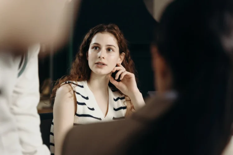 Kvinde taler assertivt og fotograferes tæt på mellem 2 andre mennesker