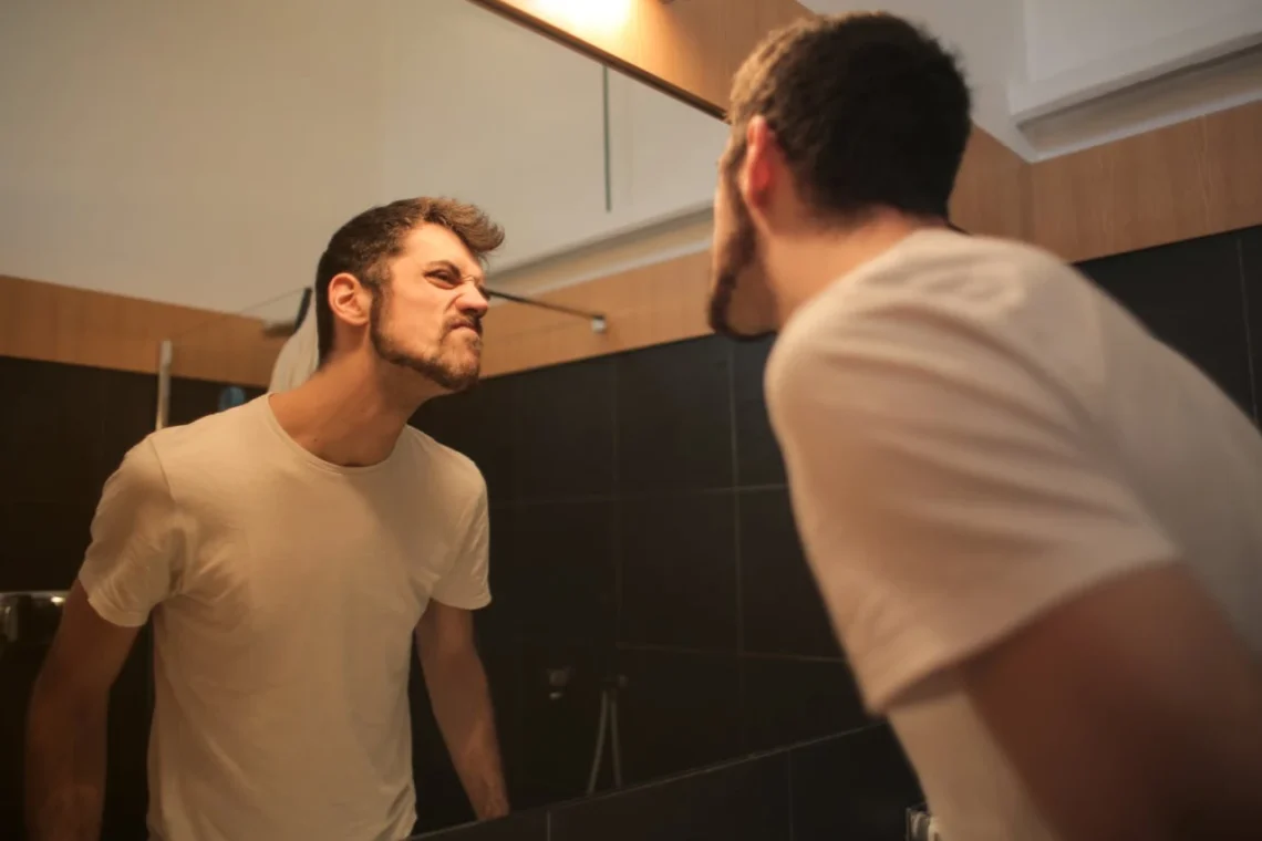Mand kigger sig kritisk i et spejl som udtryk for refleksion