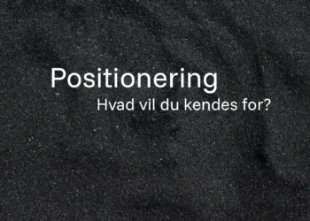 Positionering skrevet med hvid tekst på strand med sorte sandkorn
