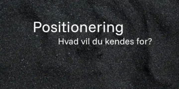 Positionering skrevet med hvid tekst på strand med sorte sandkorn