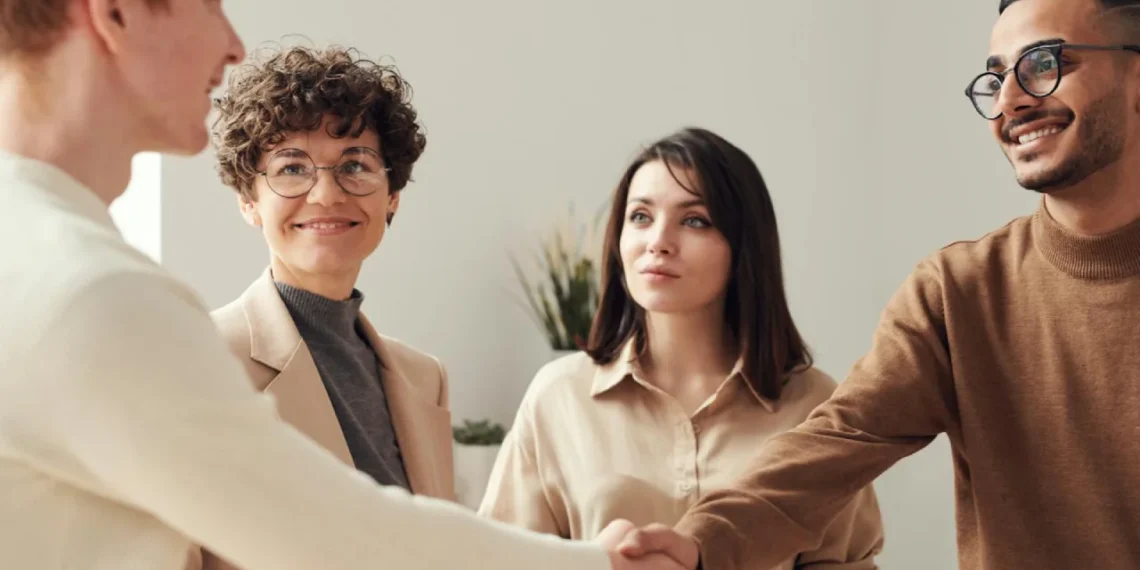2 kvinder og 2 mænd giver håndslag som udtryk for assertiv kommunikation.