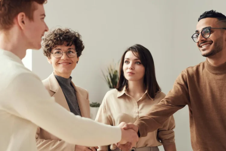 2 kvinder og 2 mænd giver håndslag som udtryk for assertiv kommunikation.