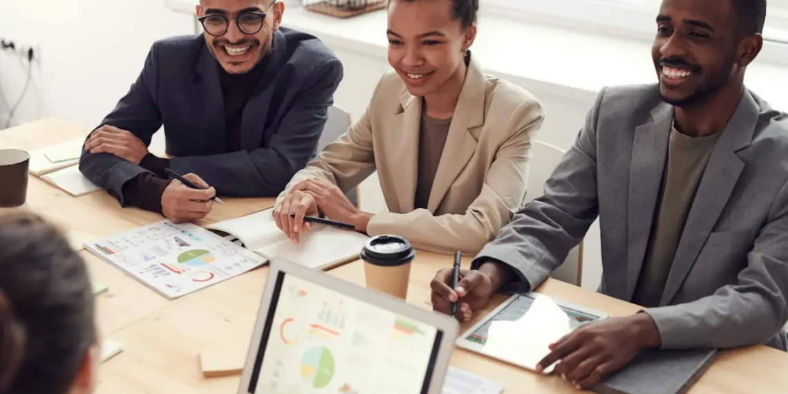 3 medarbejdere sidder ved chefens bord og smiler som compassion