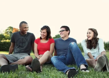 4 mennesker sidder på græsplæne og smiler som i inklusion.