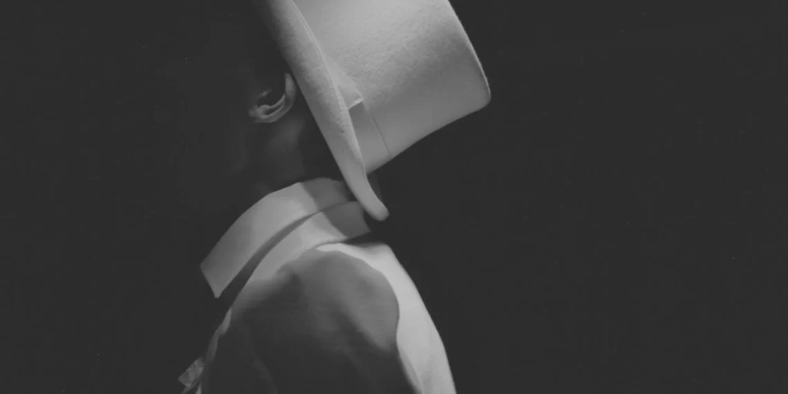 Den manipulerende leder her iklædt hvidt jakkesæt og hvid har med skjult ansigt