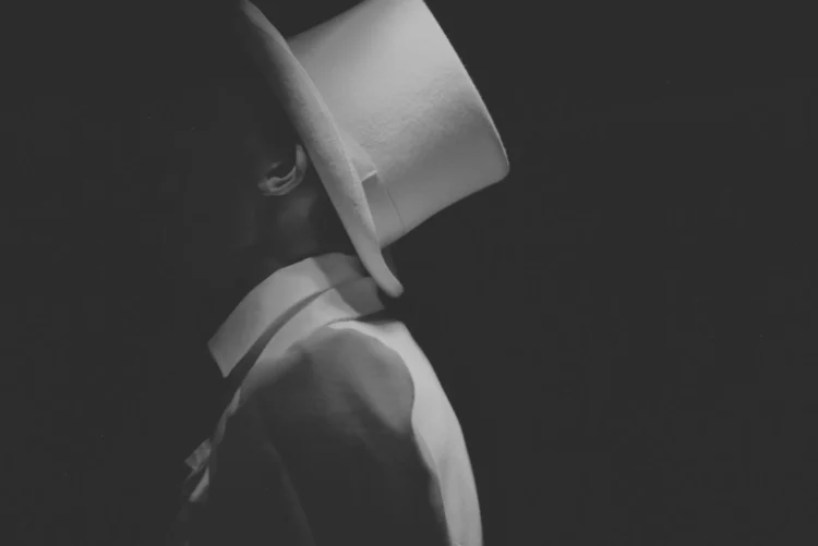 Den manipulerende leder her iklædt hvidt jakkesæt og hvid har med skjult ansigt