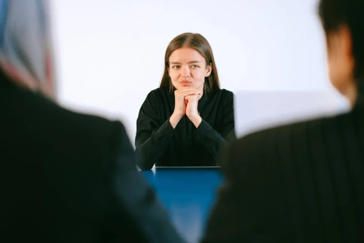 Kvinde sidder overfor interviewere i jobsamtale spørgsmål