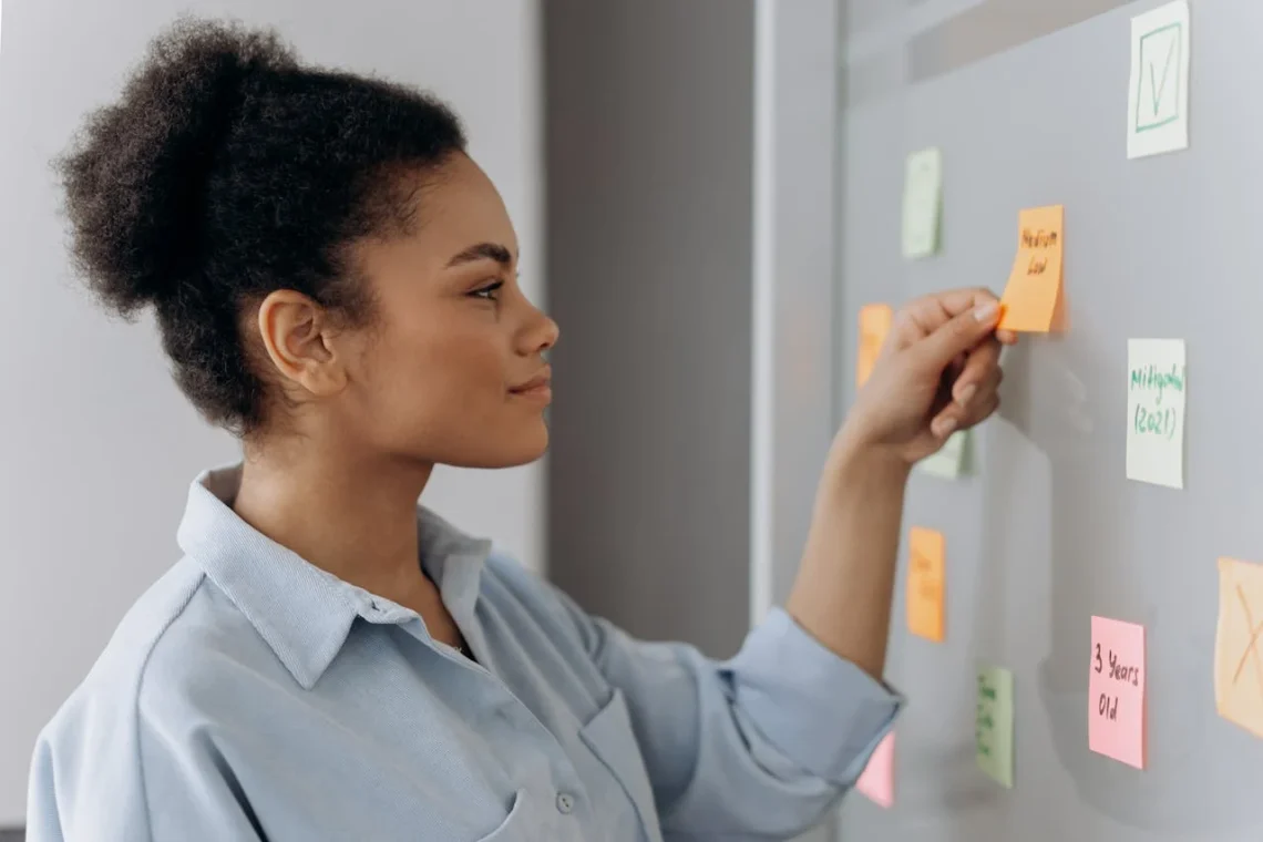 Kvinde skal prioritere på tavle med post-its