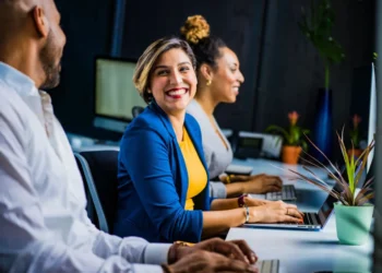 Kvinde smiler stort på arbejdet som udtryk for positiv psykologi