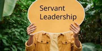 Mand holder orange skilt op med Servant Leadership